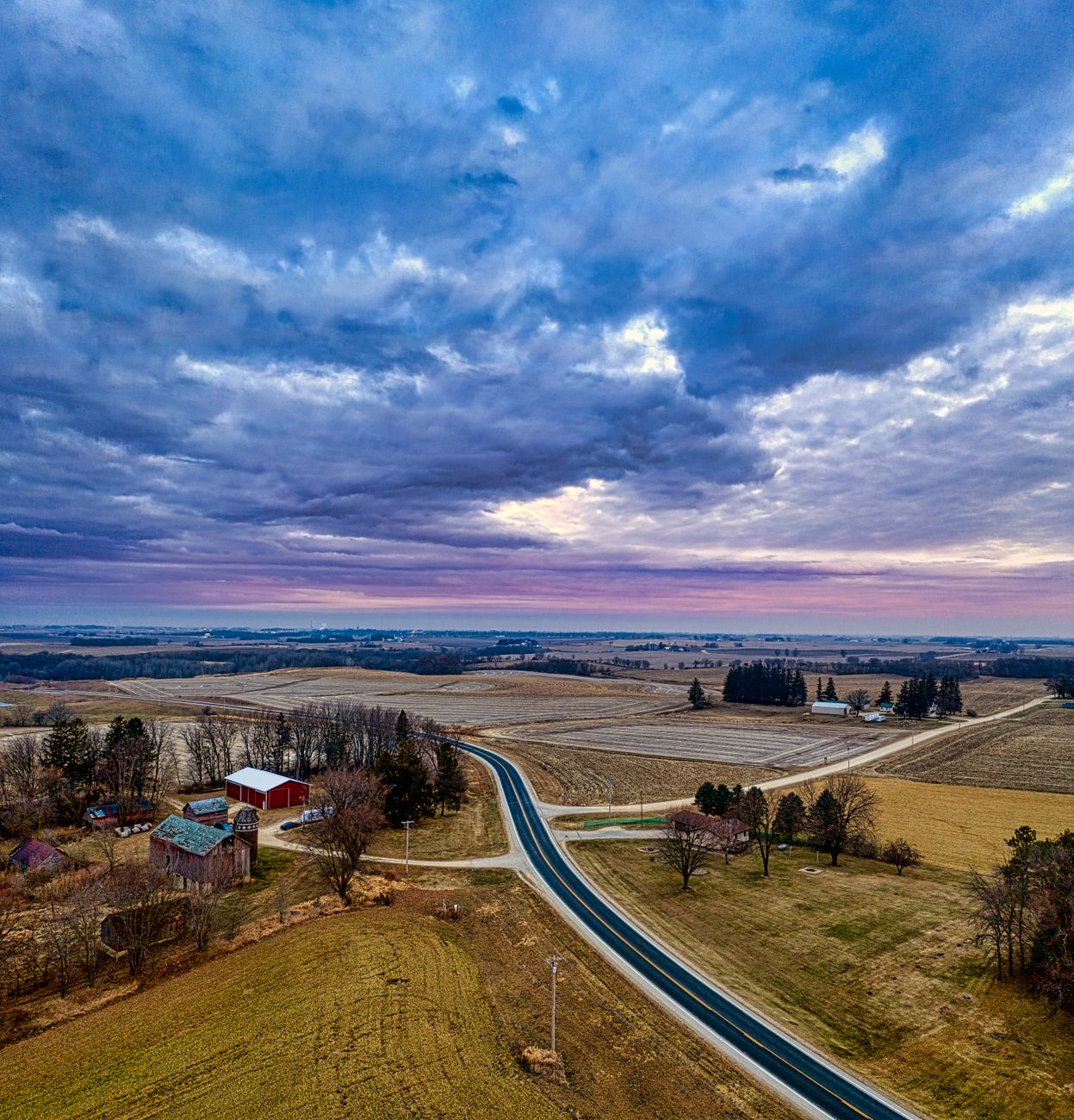 Stunning aerial landscape of rural Minnesota at sunset, showcasing fields, winding roads, and farmhouses.