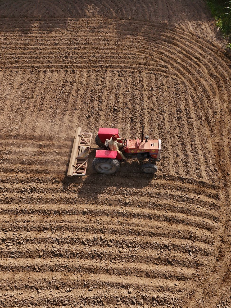 An aerial shot of a tractor plowing farm fields in Punjab, capturing rural agriculture at work.